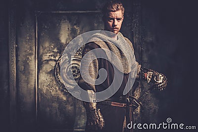 Young medieval knight posing on dark background. Stock Photo