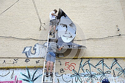 Young men activists set the poster portrait of famous Ukrainian poet and dissident Vasyl Stus on the wall of the Editorial Stock Photo