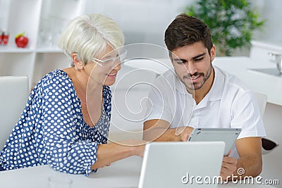 Young man and elderly lady looking at tablet screen Stock Photo