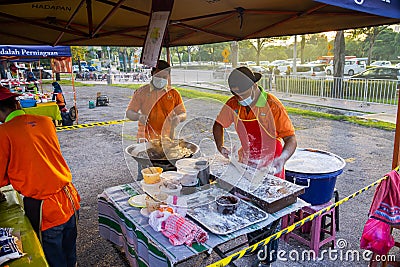 Young men frying Youtiao or Cakoi, a long golden-brown deep-fried strip of dough commonly. On a fresh market in Malaysia open air Editorial Stock Photo