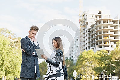 Young man and girl on the street looking at the tablet. Stock Photo