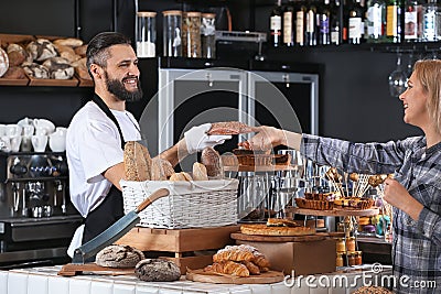 Young man giving fresh bread to woman in bakery Stock Photo