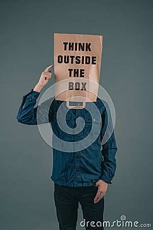 Young men has a paper bag on his head, the phrase think outside the box is standing on it, brainstorming for new ideas Stock Photo