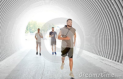 Young men or male friends running in tunnel Stock Photo