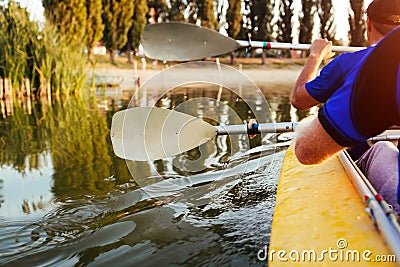 Young men rowing kayak on river at sunset. Couple of friends having fun canoeing in summer. Closeup of paddles Stock Photo