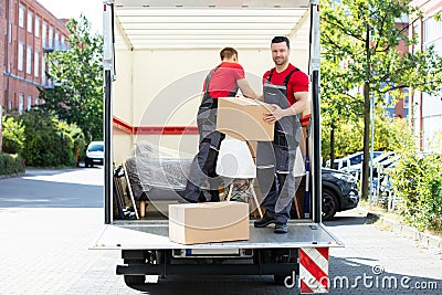 Young Men Stacking The Cardboard Boxes In Moving Truck Stock Photo