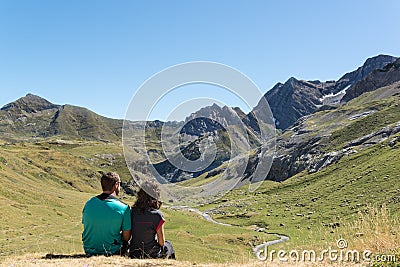 Young couple sitting down and looking at a valley in Pyrenees. Stock Photo
