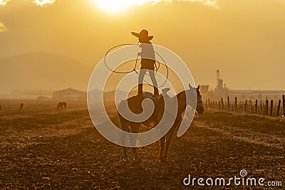 A Young Mexican Charro Cowboy Rounds Up A Herd of Horses Running Through The Field On A Mexican Ranch At Sunrise Stock Photo