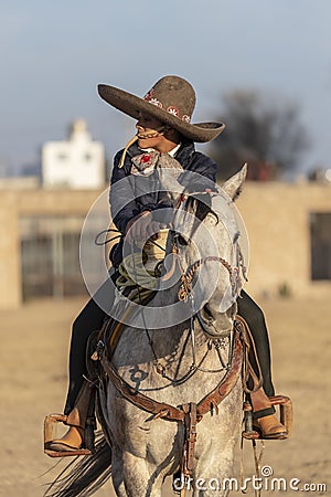 A Young Mexican Charro Cowboy Rounds Up A Herd of Horses Running Through The Field On A Mexican Ranch At Sunrise Stock Photo