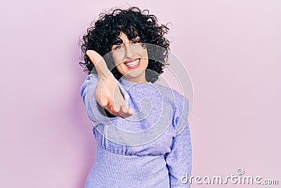 Young middle east woman wearing casual clothes smiling friendly offering handshake as greeting and welcoming Stock Photo