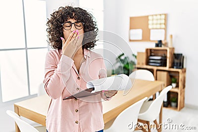 Young middle eastern woman wearing business style at office bored yawning tired covering mouth with hand Stock Photo