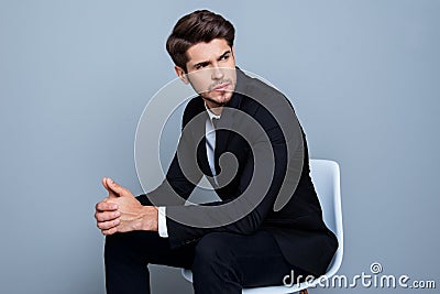 Young minded businessman in black suit sitting on chair Stock Photo