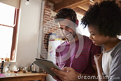 Young mixed race couple using tablet in kitchen, close up Stock Photo