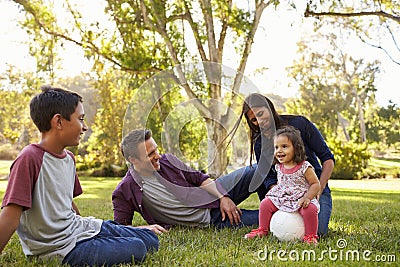 Young mixed race family relaxing with soccer ball in a park Stock Photo