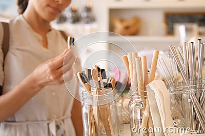 Young Mixed Race Woman Choosing Bamboo Eco Friendly Biodegradable Toothbrush in Zero Waste Shop. No plastic Conscious Minimalism Stock Photo