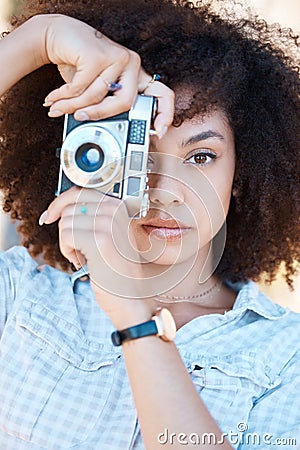 Young mixed race woman with curly hair taking creative photos on a vintage retro film camera. One female photographer Stock Photo