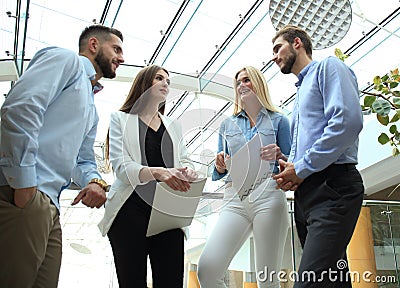 Young modern colleagues in smart casual wear having a brainstorm meeting while standing in the creative office. Stock Photo