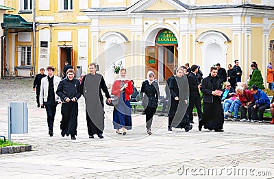 Young monks walk in Trinity Sergius Lavra along with visitors. Editorial Stock Photo