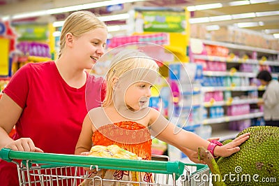 Young mother and adorable girl in shopping cart looks at giant j Stock Photo