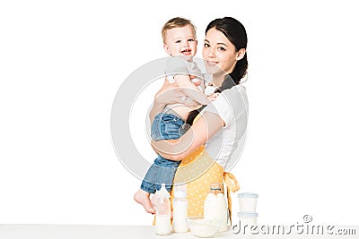 young mother in apron holding baby boy at table with children food Stock Photo