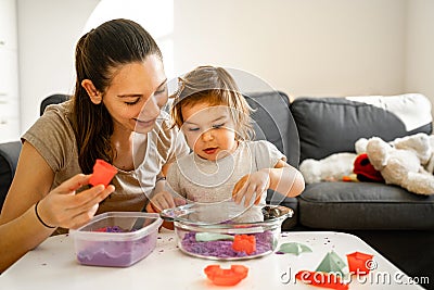 Young mother with child playing kinetic sand. Happy bonding time together. Creativity development Stock Photo