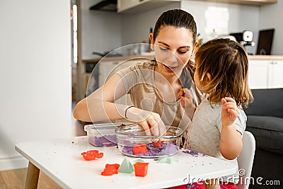 Young mother with child playing kinetic sand. Happy bonding time together. Creativity development Stock Photo