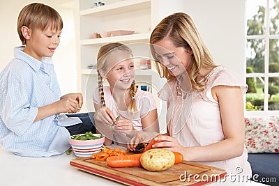 Young mother with children peeling vegetables Stock Photo