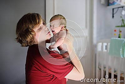 Young mother with crying newborn baby at home. Baby cry during colic Stock Photo