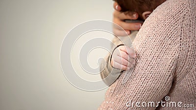 Young mother cuddling adorable infant in arms, tiny hand closeup, baby care Stock Photo