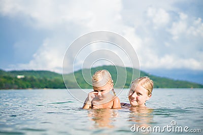 Young mother and daughter have fun swim on island in tropical ocean Stock Photo