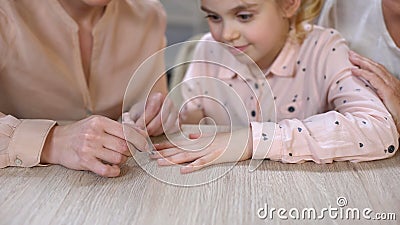 Young mother doing manicure for daughter, spending time together, female leisure Stock Photo