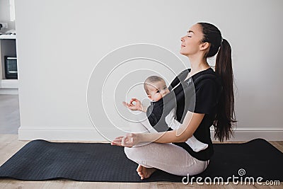 Young mother doing yoga with baby in ergo backpack Stock Photo