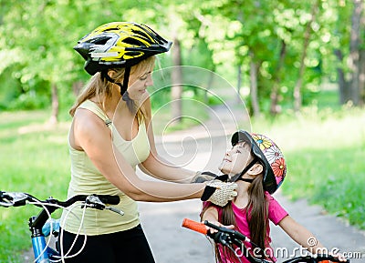 Young mother dresses her daughter's bicycle helmet Stock Photo