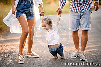 Young mother and father hold the hands of child and swing her Stock Photo