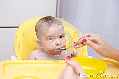 Mother feeding her baby son with fruit puree Stock Photo
