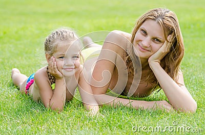 Young mother and five year old daughter lying on green grass and looking to frame Stock Photo