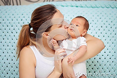 Young mother gently hugs her newborn baby. Mothers Day. Woman kisses her baby Stock Photo