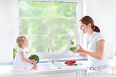 Young mother and her cute toddler daughter cooking Stock Photo