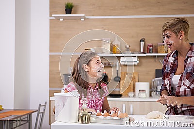 Young mother and her teenage daughhter playing with flour while making delicious food. Stock Photo