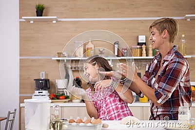 Young mother and her teenage daughhter playing with flour while making delicious food. Stock Photo