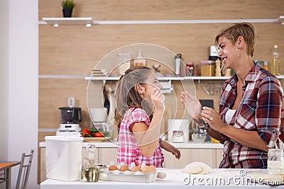 Young mother and her teenage daughhter playing with flour while making delicious food. Stock Photo