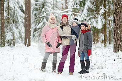 Young mother and her three kids having fun outdoors. Two young girls and their baby boy sibling on winter day. Kids with large age Stock Photo