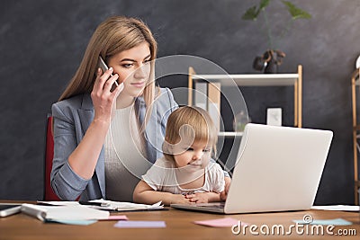 Young mother holding baby while talking on phone Stock Photo