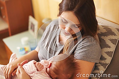 Young mother holding her newborn child. Mom nursing baby. Family Stock Photo