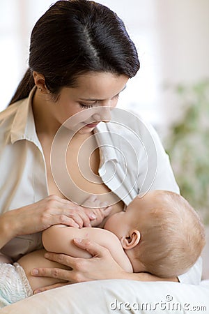 Young mother holding her newborn child. Mom nursing baby. Pretty woman breastfeeding kid. Stock Photo