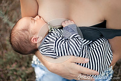 Young mother breastfeed newborn baby on walk. Close up. Stock Photo