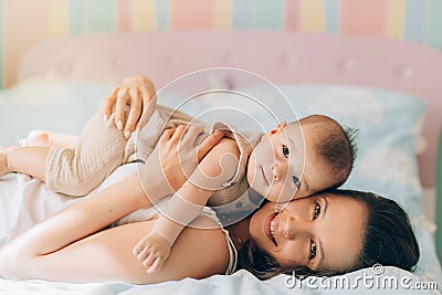 Young mother hugs her mixed race child. Child adoption and In Vitro Fertilization IVF . Asian baby and indian mom lying Stock Photo