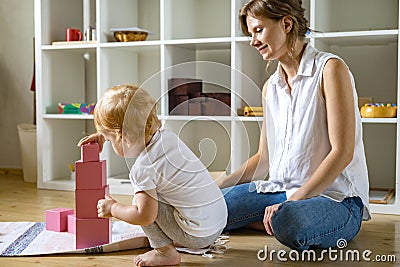Young mother and little baby assembling pink cube Maria Montessori ecological materials Stock Photo
