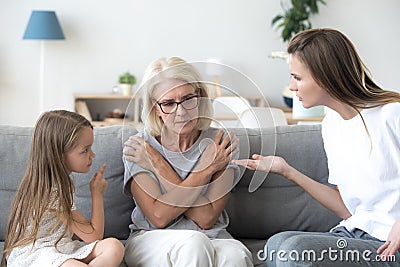 Young mother and little daughter scolding upset grandmother, gen Stock Photo