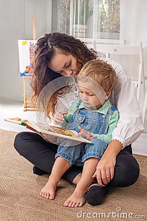 Young mother or nanny with small child boy sit on the floor on a Stock Photo